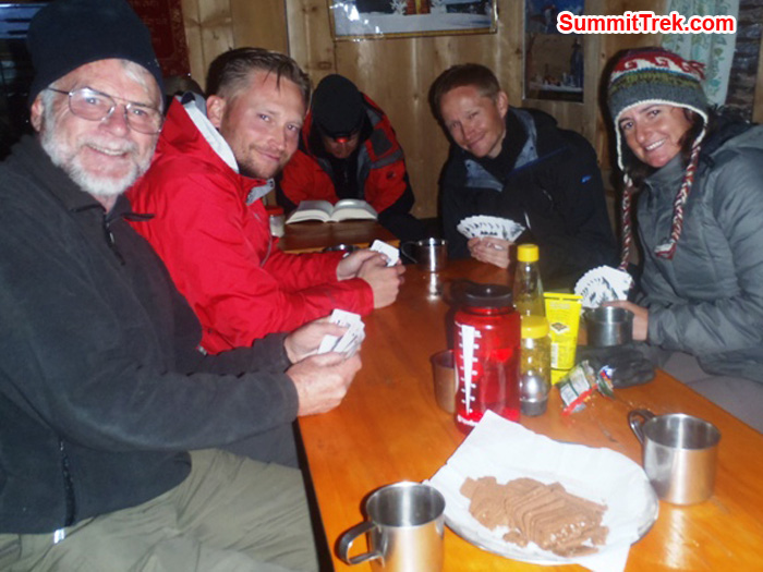 Pete Downie, James Kaminski, Joel Kaminski, and Carla Strong compete in the team bridge tournament while Milan Sramek reads a book, in Kote Village. Photo by Andrew Davis.