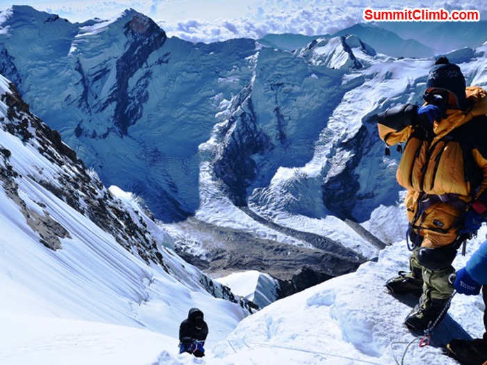 Jangbu Sherpa stands atop the summit of Mera Peak and monitors the rope he fixed while Felipe from Brazil ascends. Photo by Michael Moritz.