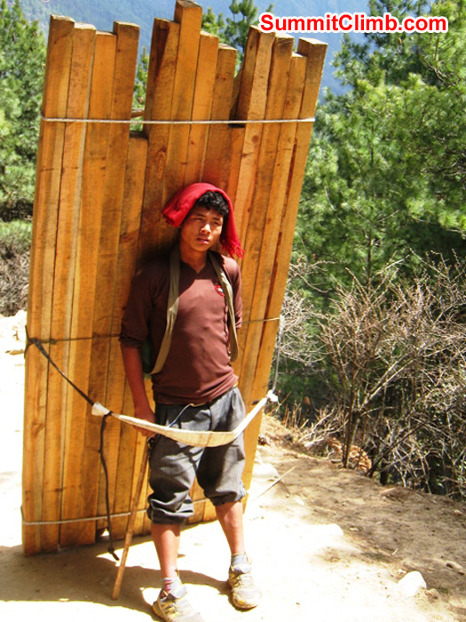 Wood merchant on the path to Everest. He cut these boards himself in the lowlands and is carrying them to sell. Weight is 100kg - 220 lbs. Photo Scott Smith