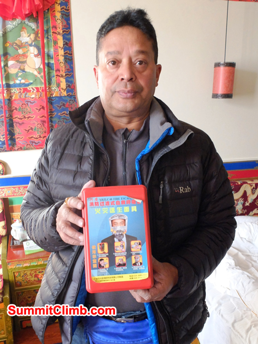Murari Sharma holding emergency oxygen hood in Shigatse hotel room