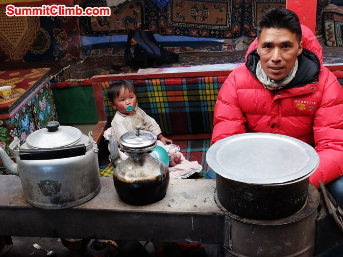 Tenji Sherpa and little Tsering warming around the stove in the house where our Cho Oyu and Shishapangma expedition supplies are stored